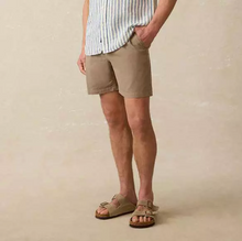 Load image into Gallery viewer, Man wearing khaki-brown shorts with a button down shirt and sandals on a tan background