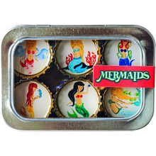 Load image into Gallery viewer, A square metal tin containing six bottle-cap style magnets, each printed with a different mermaid illustration in colorful sea-themed designs. A red label on the right reads “MERMAIDS.