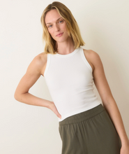 Load image into Gallery viewer, Woman wearing a white sleeveless top and green pants against a plain background