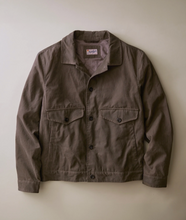 Load image into Gallery viewer, A dark brown utility jacket with a button-up front, two buttoned chest pockets, and a classic collar, laid flat against a neutral beige background.
