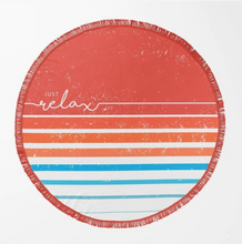Load image into Gallery viewer, A round beach towel with a distressed retro design, featuring horizontal stripes in terracotta, orange, light blue, and white, with the words 'JUST relax' printed on the left side. The towel has fringed edges and is displayed flat against a clean white background.