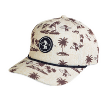 Load image into Gallery viewer, A beige baseball cap with a brown palm tree and surfer print, featuring a black circular patch on the front with a white surfer logo.