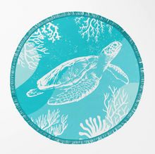 Load image into Gallery viewer, Round beach towel with a fringed edge featuring a white sea turtle and coral reef illustration on a light blue background, shown on a plain white background.