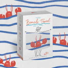 Load image into Gallery viewer, A white product box for a Turkish Beach Towel by Marina & Co, featuring a clear window that displays a striped beach towel with red lobster illustrations. The box is set against a matching striped fabric background with red lobster prints.