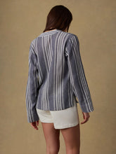 Load image into Gallery viewer, Person wearing a blue and white striped shirt and white shorts on a beige background