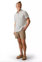 Load image into Gallery viewer, Man wearing khaki-brown shorts with a button down shirt and sandals on a tan background
