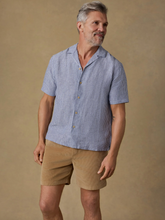 Load image into Gallery viewer, Man wearing a blue striped shirt and beige shorts against a brown background
