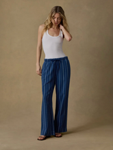 Load image into Gallery viewer, Woman wearing a white tank top and blue striped pants against a beige background
