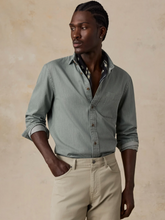 Load image into Gallery viewer, Man wearing a sage green button down shirt with khaki pants in front of a beige wall
