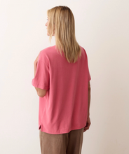 Load image into Gallery viewer, A woman with blonde hair is shown from the back wearing a dusty pink short-sleeve top and brown pants against a plain off-white background.
