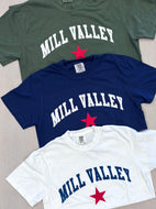 Stack of three t-shirts that say Mill Valley with a red star, tee colors are olive green, navy blue and white