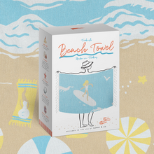 Load image into Gallery viewer, A white product box for a Turkish Beach Towel, featuring a blue towel illustration with a beachgoer on a surfboard and the text 'Turkish Beach Towel Made in Turkey'. The box is set against a beach-themed background with umbrellas and towels.
