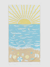 Load image into Gallery viewer, A rectangular beach towel with white fringe at the top and bottom, featuring a stylized ocean scene with a yellow sun over light blue water and a sandy beach with beach accessories at the bottom.
