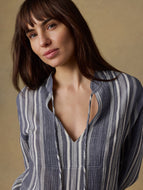 Woman wearing a blue and white striped shirt against a beige background