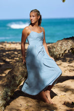 Load image into Gallery viewer, Woman in a blue dress standing on a beach with ocean in the background

