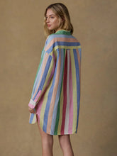 Load image into Gallery viewer, Woman wearing a colorful striped dress against a brown background
